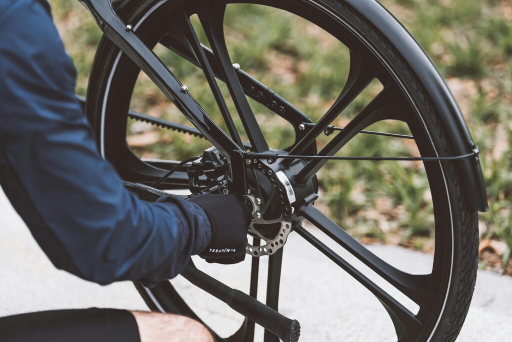 Close-up of a man fixing a bicycle wheel outdoors, showcasing mechanical details and tools.